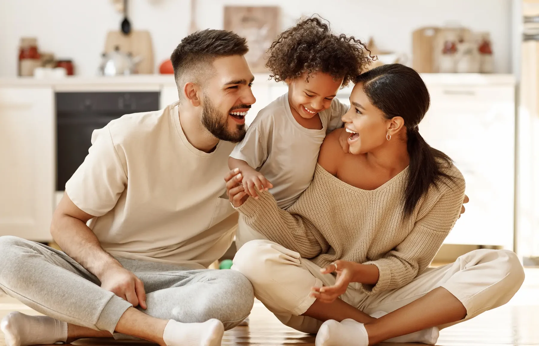 Young family sitting on the floor smiling and laughing