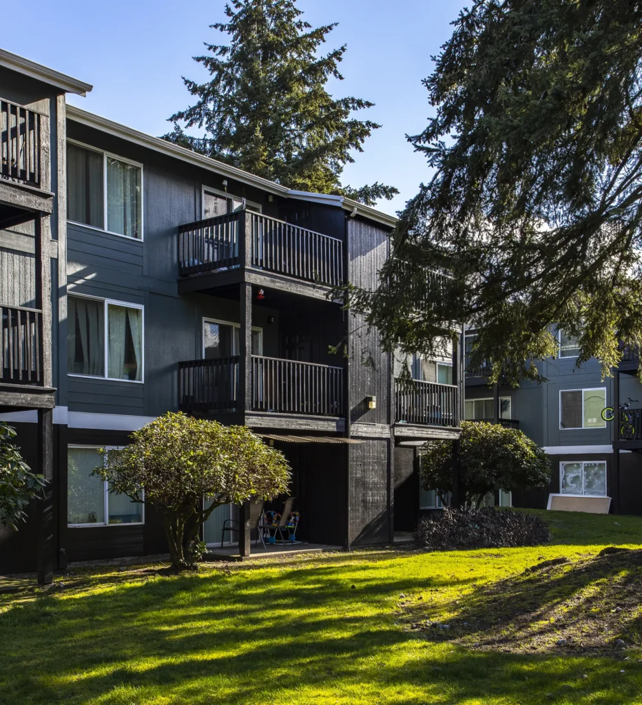 Building exterior with private balconies and large trees.